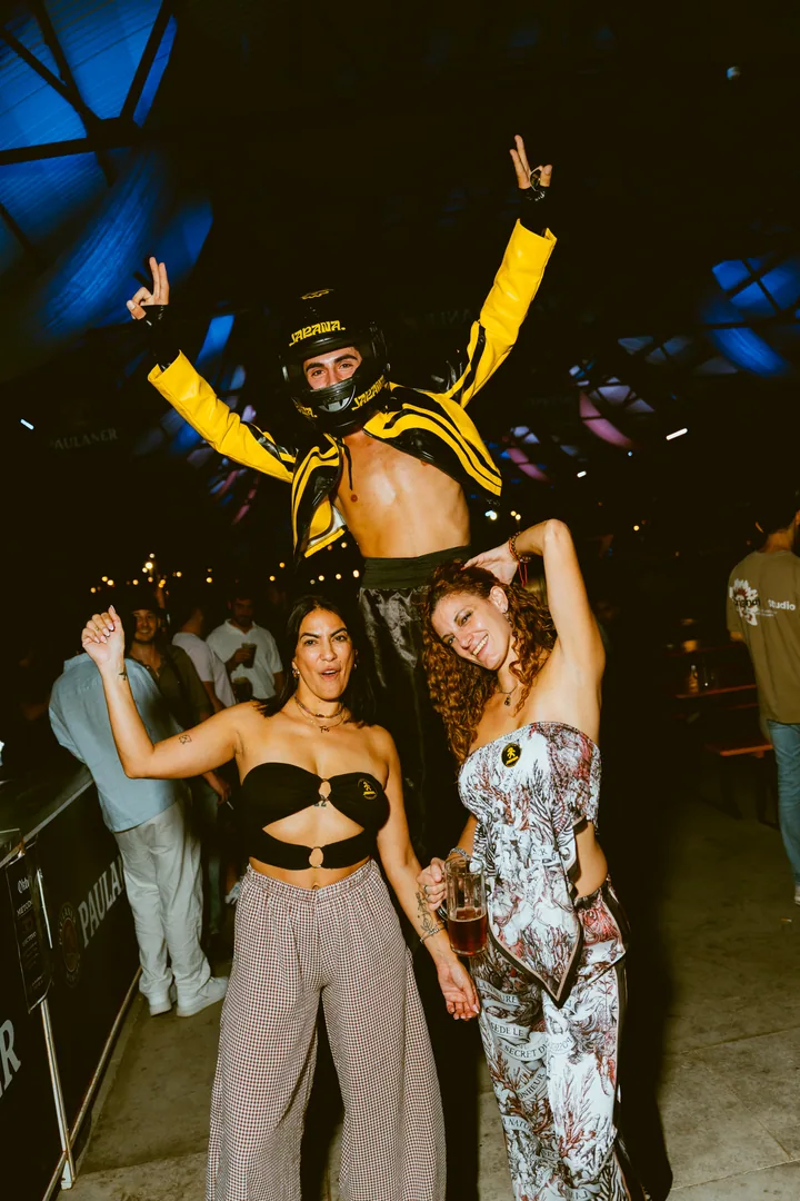 Un zancudo con casco y chaqueta amarilla de JARANA posa con dos chicas en Berlin Social Club.